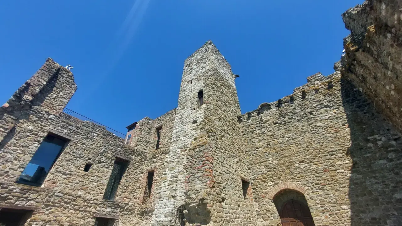 Rovine di un castello nel centro storico di Passignano sul Trasimeno, con mura in pietra e cielo azzurro.