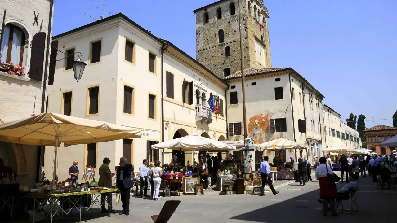 Mercato in piazza a Portobuffolè cosa vedere: bancarelle di antiquariato e la torre civica sullo sfondo.