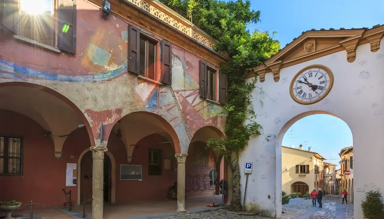 Un angolo suggestivo tra i borghi da visitare in Romagna. Archi affrescati, un portale con orologio e un vicolo acciottolato invitano alla scoperta.