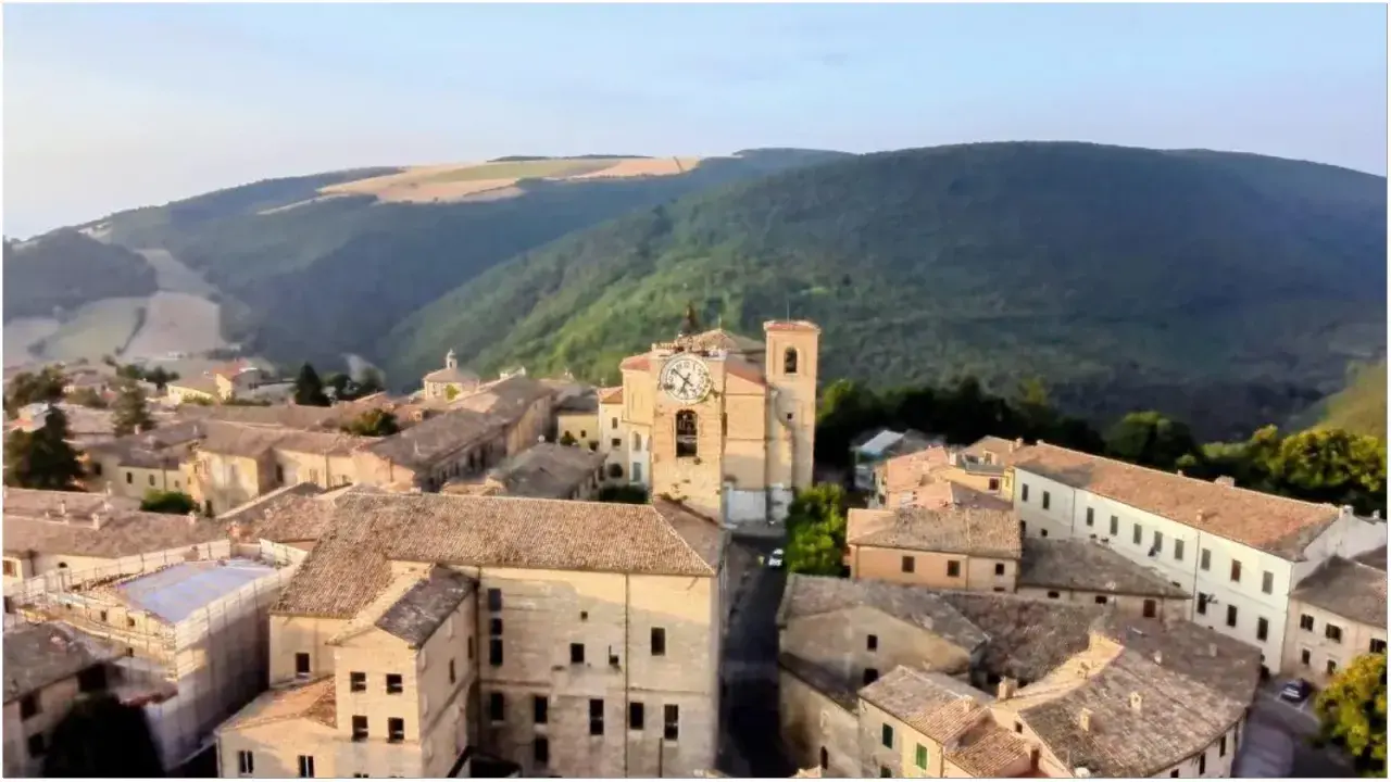 Borgo con torre dell'orologio, immerso nel verde delle colline. Chissà se è questo il borgo dei borghi vincitore.