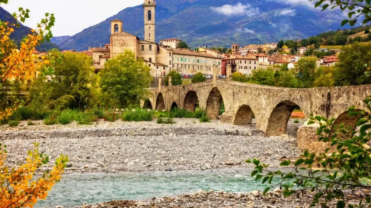 Ponte Gobbo a Bobbio, borgo dei borghi, con il fiume e le montagne sullo sfondo.
