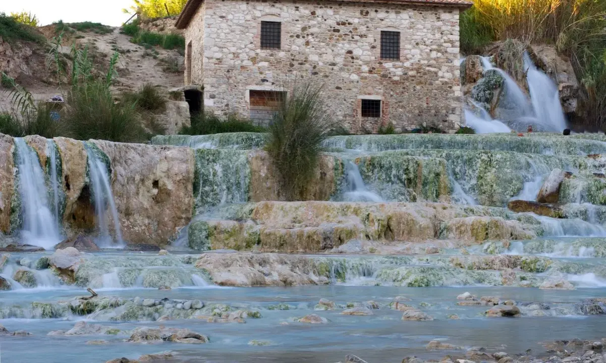 Cascate termali naturali con un antico mulino in pietra, un'oasi di benessere nel cuore delle terme centro Italia.