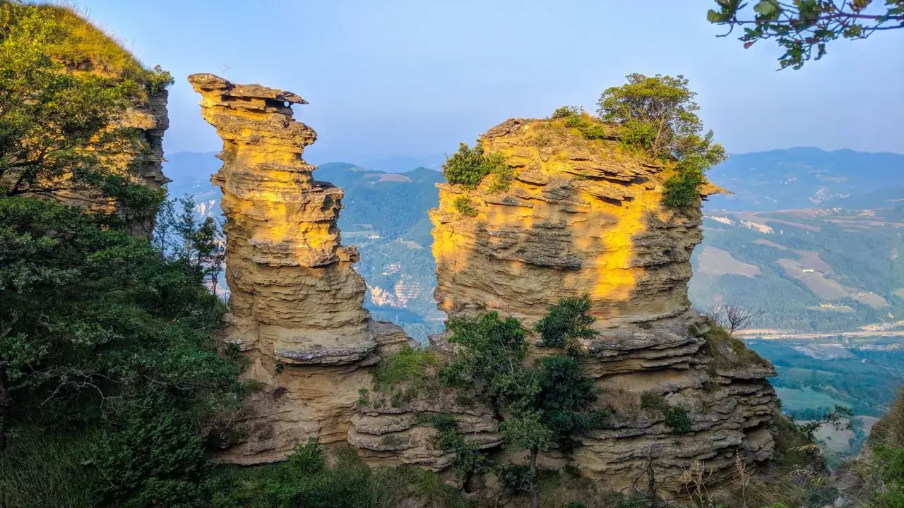 Formazioni rocciose suggestive illuminate dal sole, un paesaggio mozzafiato che ricorda le tappe del cammino della Via degli Dei.