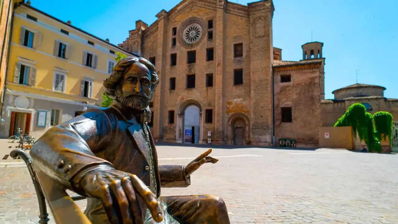 Statua di bronzo in piazza, con edifici storici sullo sfondo. Un assaggio delle città più belle Emilia Romagna.