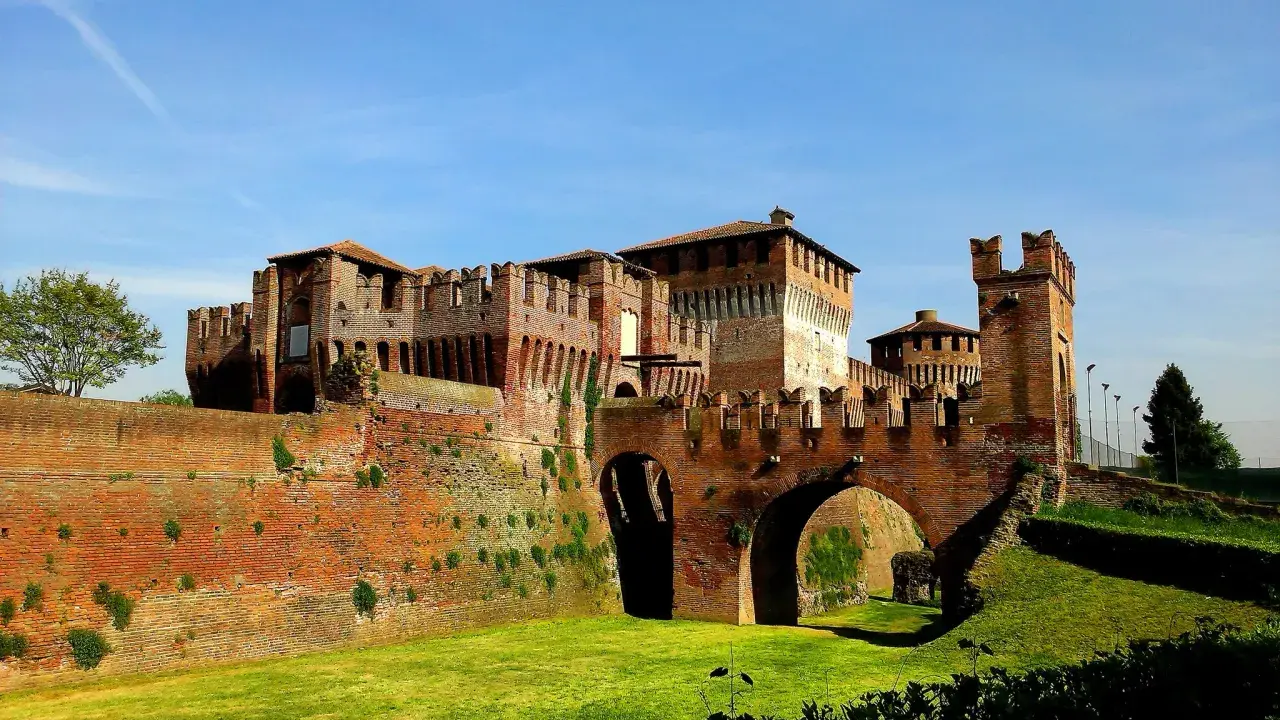Castello Sforzesco, uno dei borghi belli vicino Cremona, con mura in mattoni rossi, ponti ad arco e fossato verde.