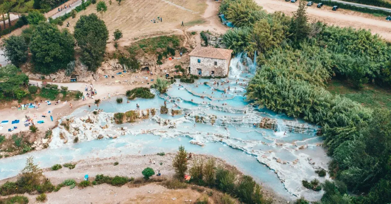 Una perfetta gita domenicale toscana: cascate termali azzurre e gente che si rilassa tra le rocce.