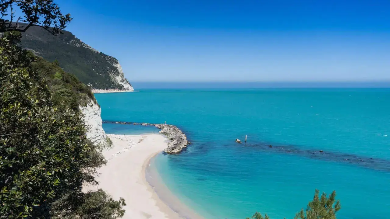 Spiagge piu belle d'Italia: una caletta di sabbia bianca incastonata tra scogliere a picco e un mare turchese cristallino.