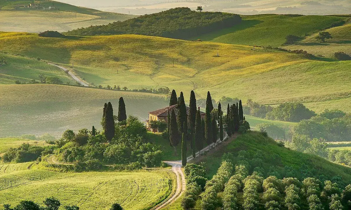 Colline toscane con cipressi e casale, un'immagine iconica dei borghi da visitare in Toscana.