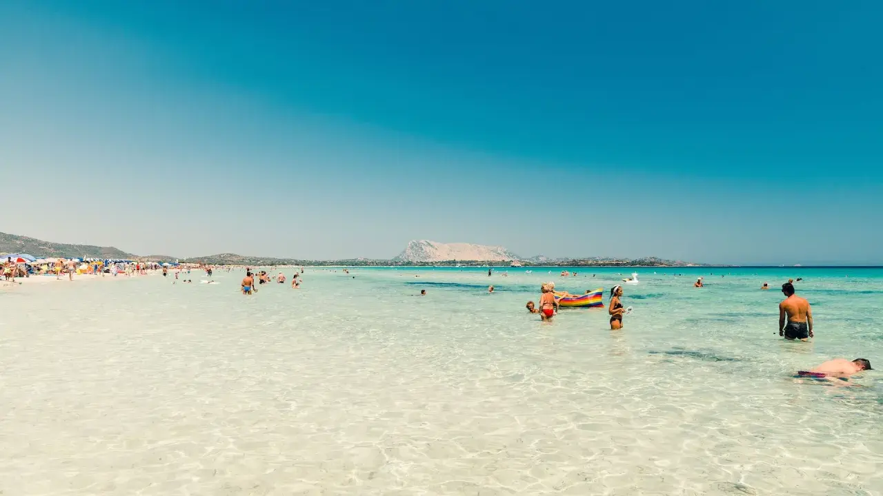 Acque cristalline e gente felice in spiaggia, forse qual è la parte più bella della Sardegna? Un paradiso azzurro.