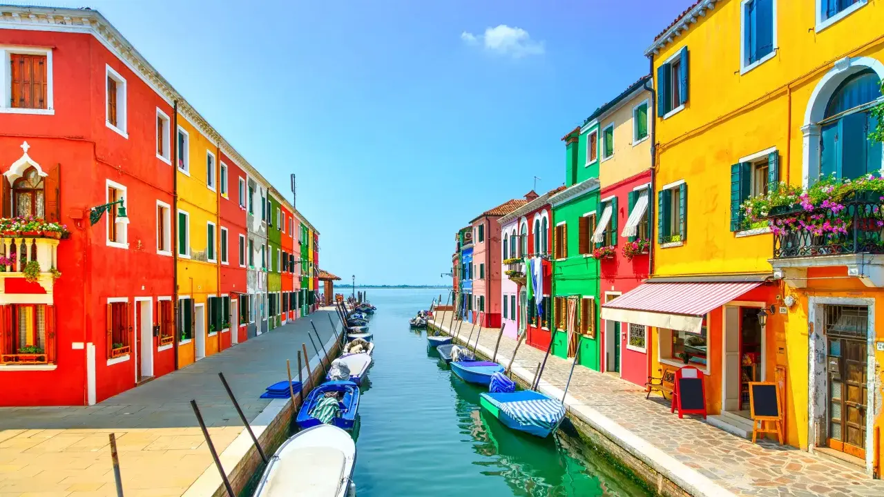 Colorate case affacciate su un canale con barche ormeggiate, un'incantevole scena di **Murano e Burano**.