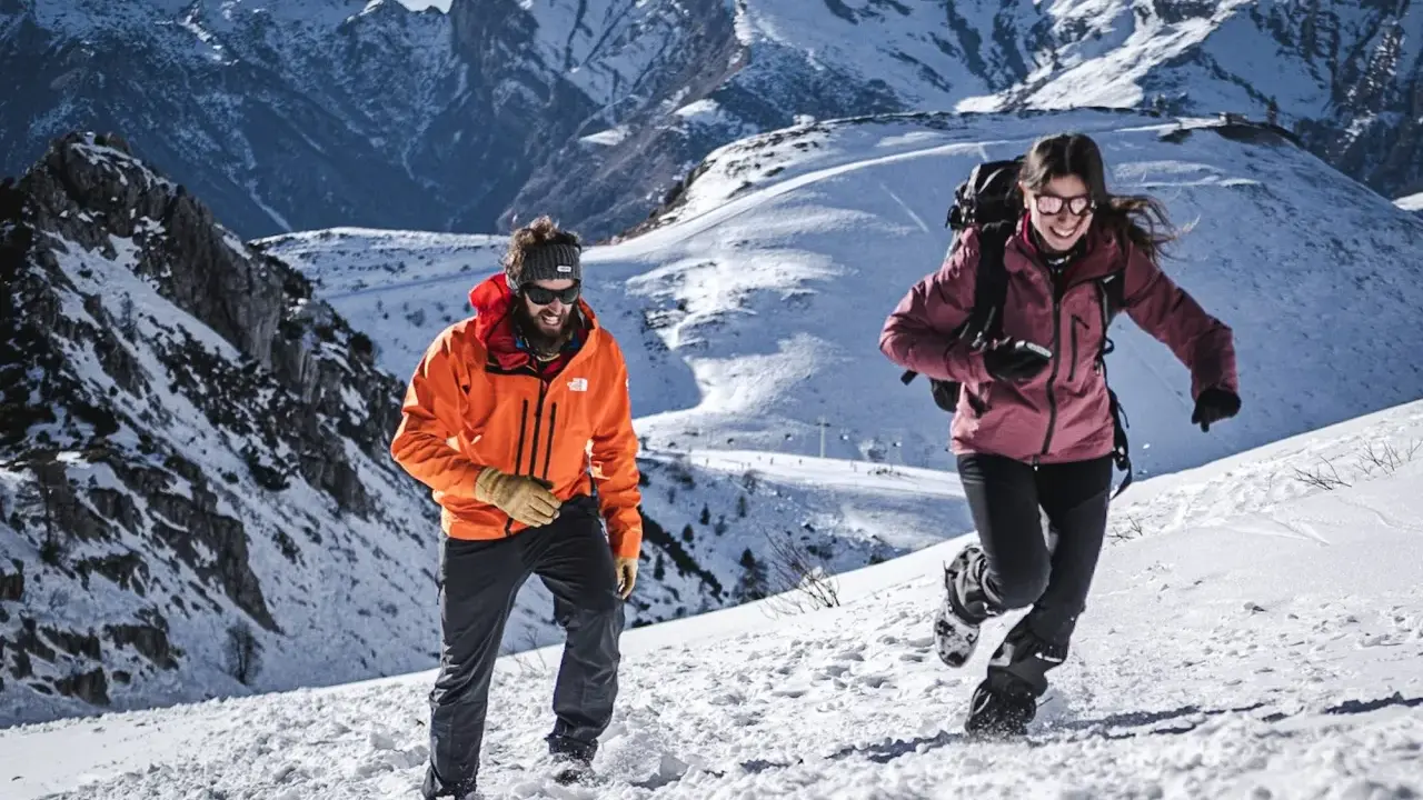 Coppia in montagna con abbigliamento da neve, godendosi l'estate in un paesaggio innevato.