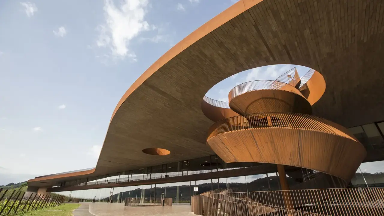 Architettura moderna di cantine toscana famose, con scale a chiocciola in corten e ampie vetrate che riflettono il paesaggio collinare.
