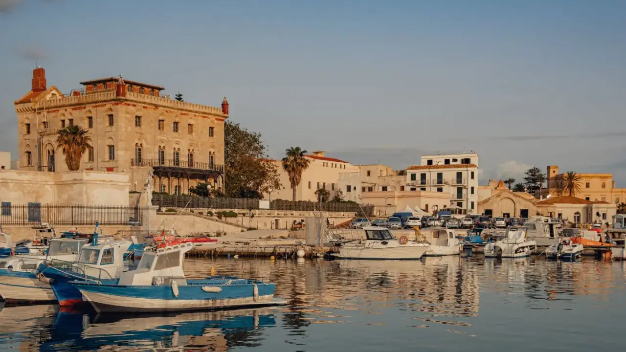 Porto di Favignana con barche ormeggiate e edifici storici. Per sapere come arrivare a Favignana, guarda questo porto!