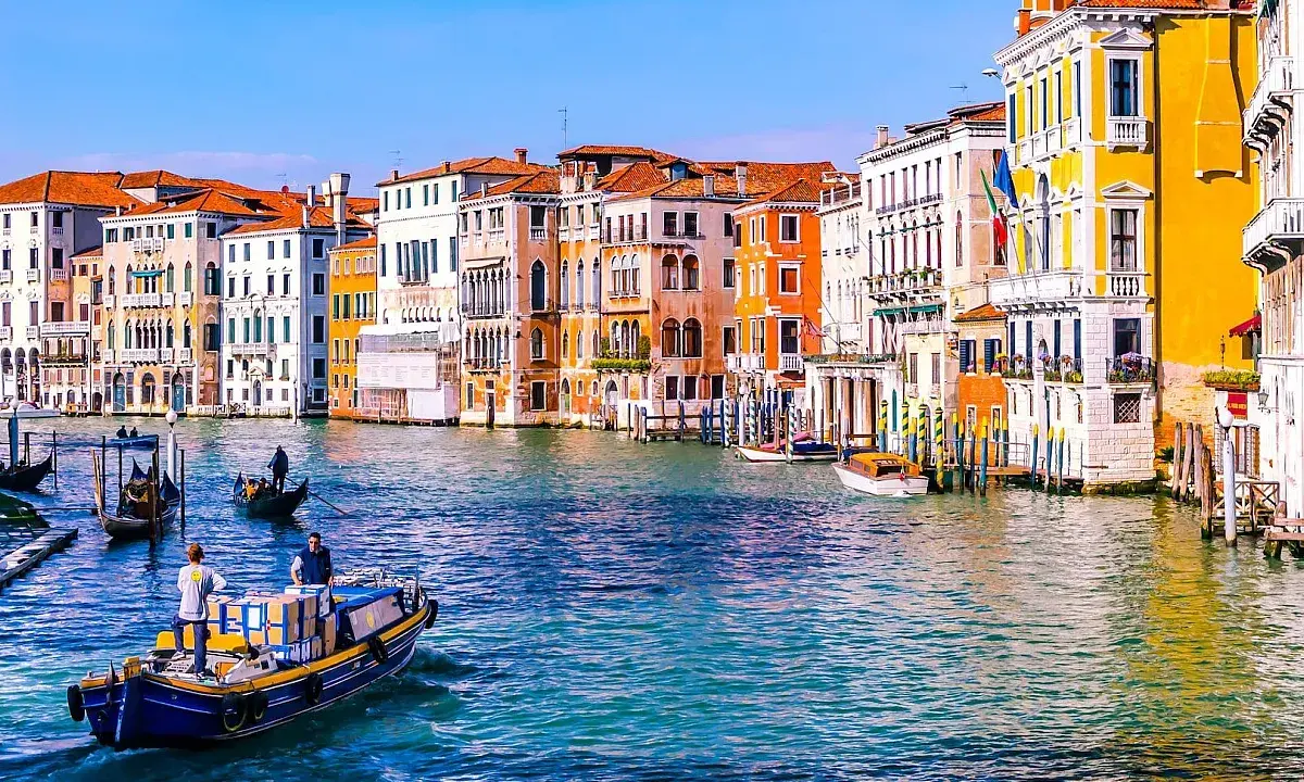 Gondole e vaporetti sul Canal Grande, un assaggio di cosa vedere a Venezia in due giorni. Palazzi colorati e acqua scintillante.