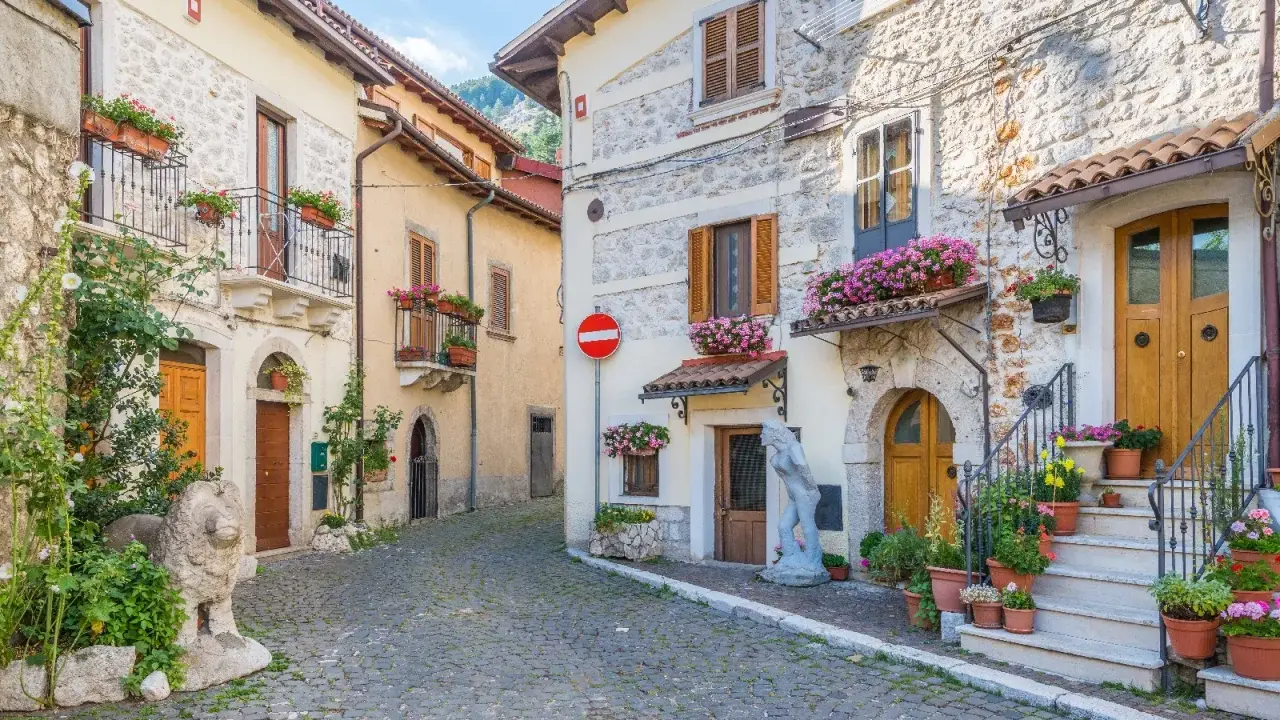 Antica via acciottolata tra **borghi Abruzzo sul mare**, con case in pietra e fiori colorati sui balconi.