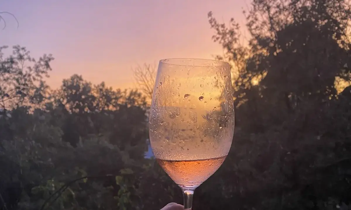 Un calice di vino rosato riflette il tramonto sulle dolci colline del Chianti.