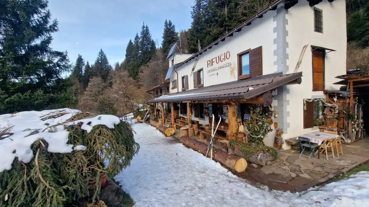 Rifugio Cimon della Bagazza, un luogo accogliente con rifugi aperti in inverno in Lombardia, circondato da neve e alberi.