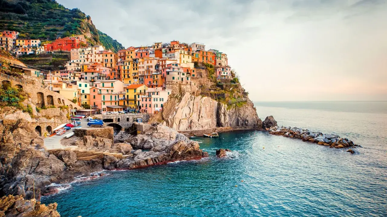 Manarola, uno dei borghi italiani da visitare, si aggrappa alla scogliera con le sue case colorate che si tuffano nel mare blu.