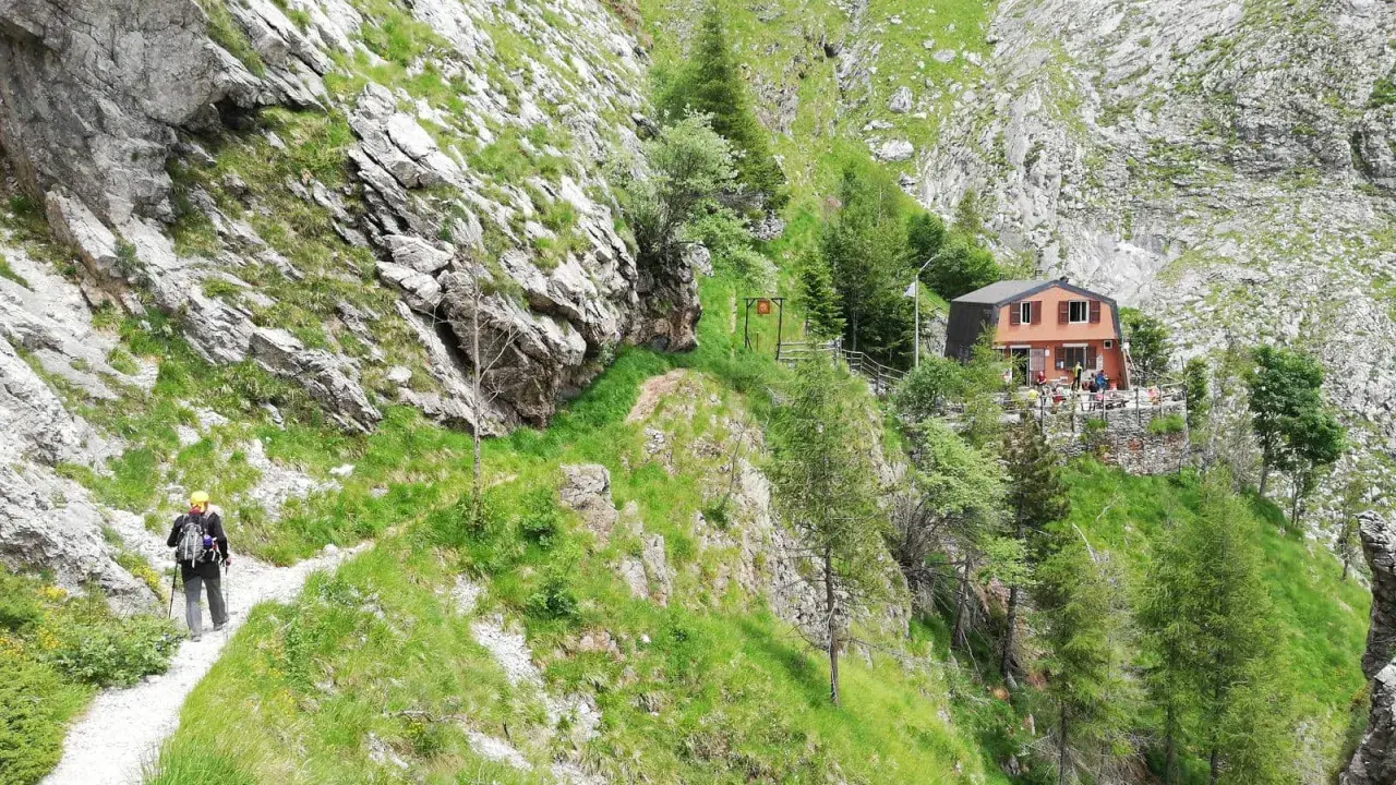 Escursionista sul sentiero della via Vandelli, con rifugio in vista.