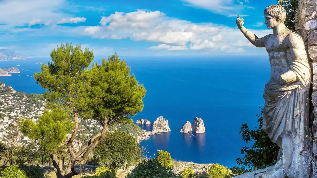 Statua antica guarda il mare blu intenso e i Faraglioni, icona dell'isola vicino Capri.