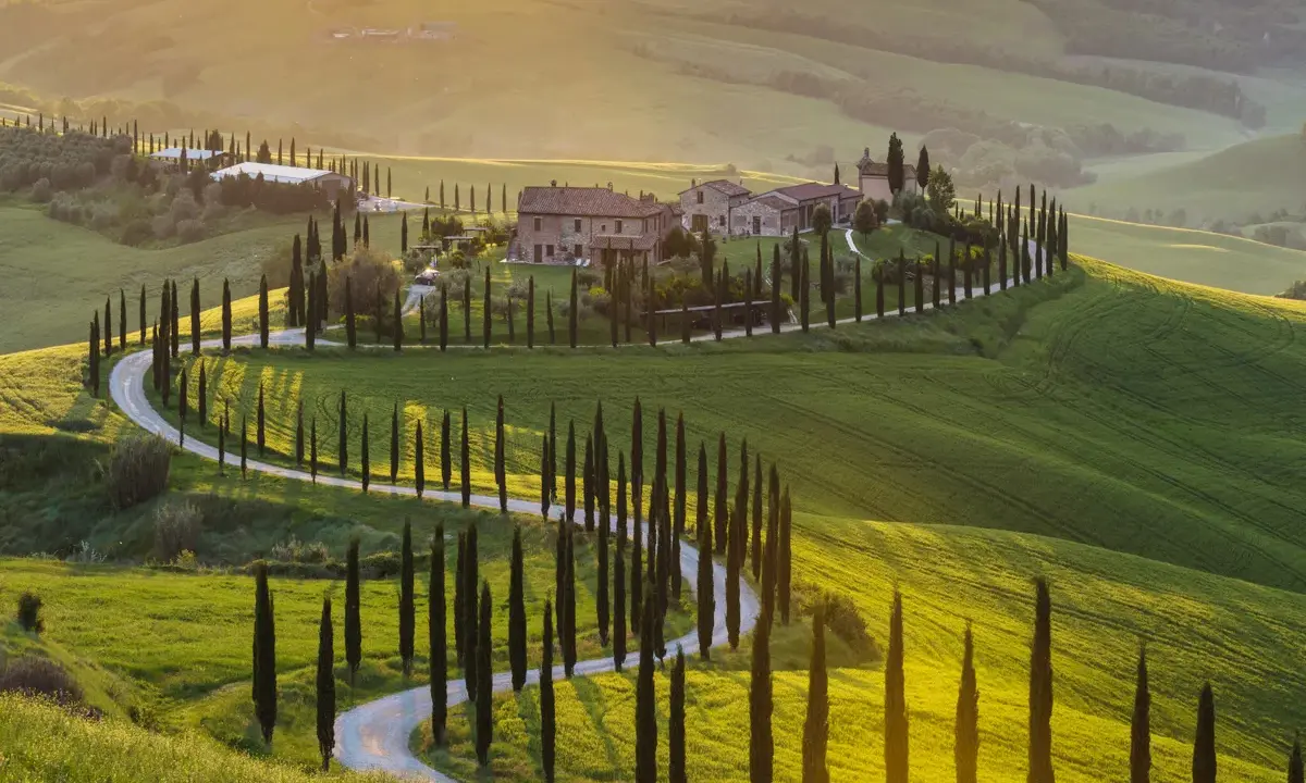 Un sogno per un tour Toscana 3 giorni: colline verdi, cipressi e un casale al tramonto.