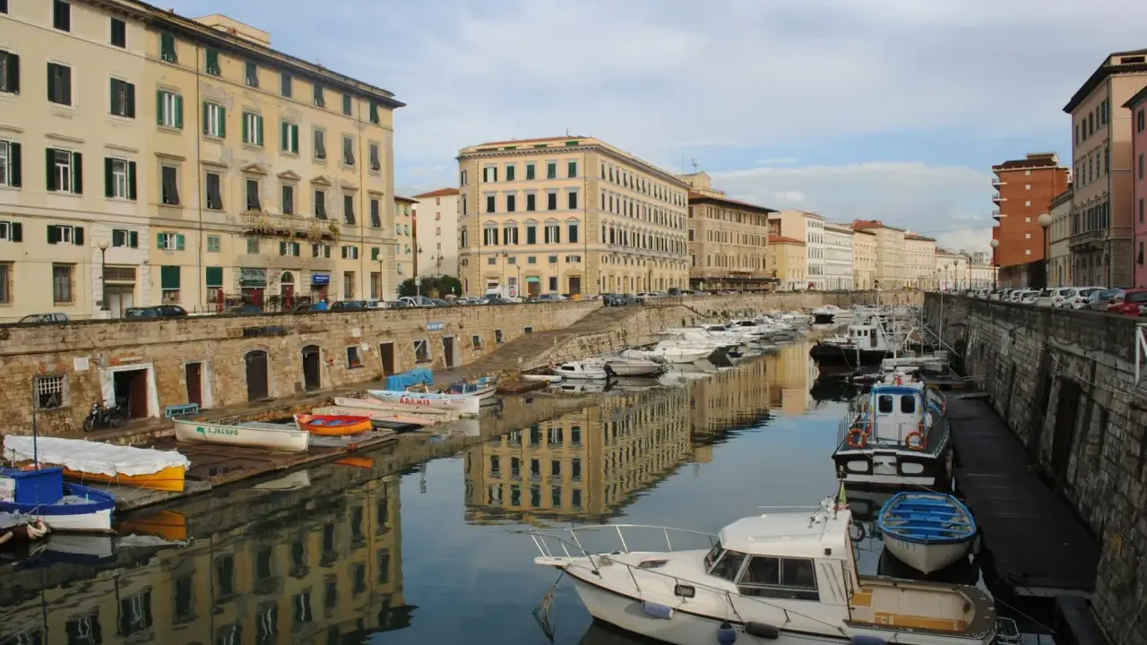 Canali e palazzi storici a Livorno, perfetti per gite di un giorno. Barche ormeggiate riflettono l'architettura.
