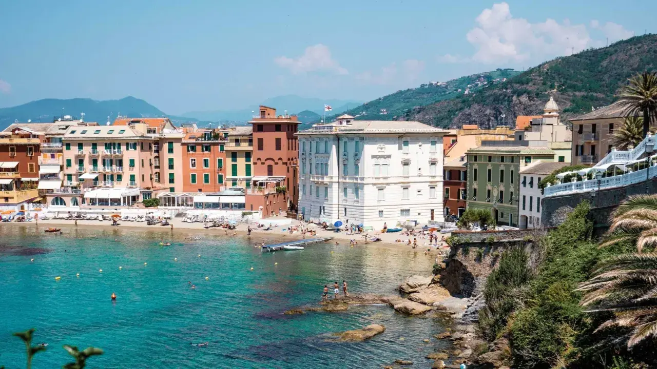 Colorate case affacciate su una spiaggia affollata e un mare turchese, tipico della riviera di Levante.