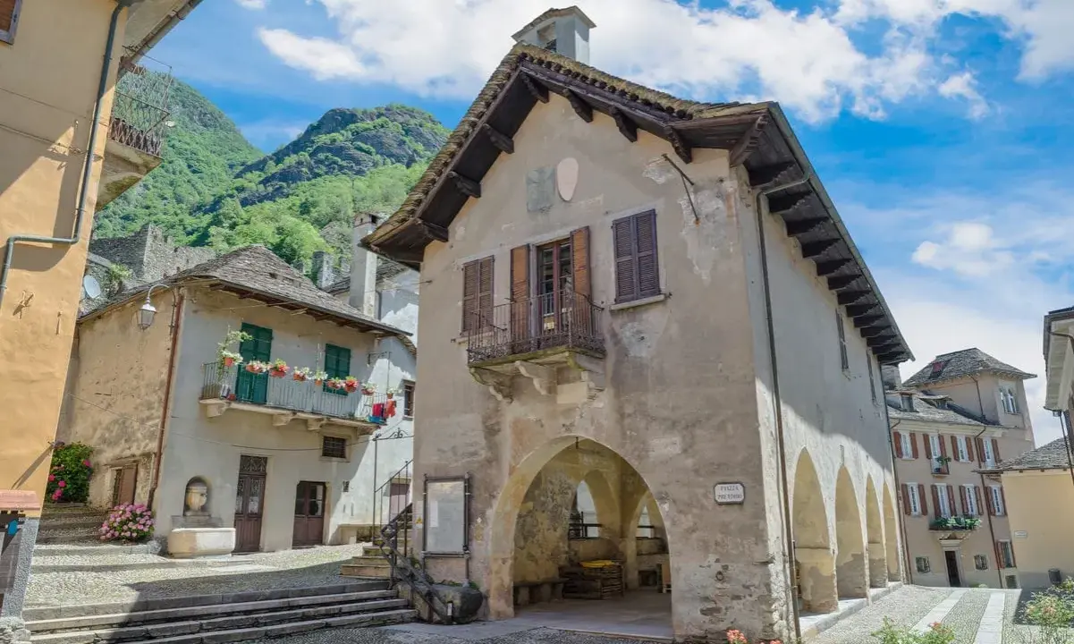 Un borgo antico con case in pietra e balconi fioriti, incastonato tra montagne verdi. Un luogo che fa venire vogogna cosa vedere, per la sua bellezza autentica.