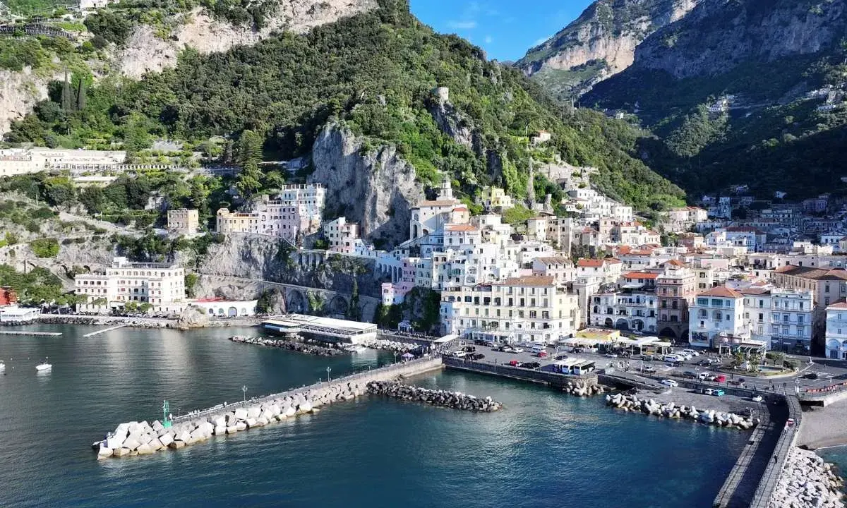 La **conca dei Marini** si apre sul mare blu, con case colorate aggrappate alla scogliera verdeggiante.