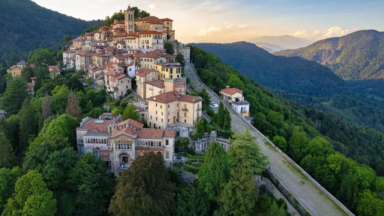 Borgo pittoresco su un colle, ideale per scoprire cose da fare a Varese. Case colorate, un campanile e sentieri panoramici tra il verde.