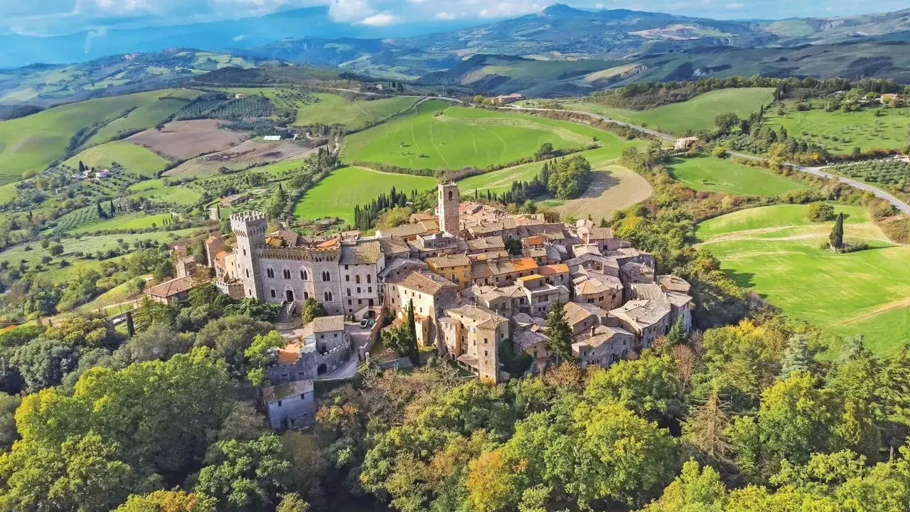 Un borgo medievale arroccato su una collina, circondato da dolci colline verdi. Un esempio dei borghi più belli della Toscana.