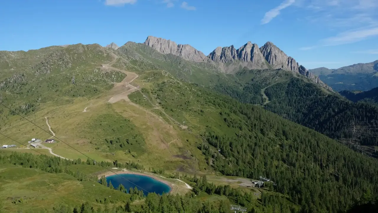 Panorami alpini con sentieri per passeggiate facili vicino a Trento, un lago azzurro e cime rocciose.