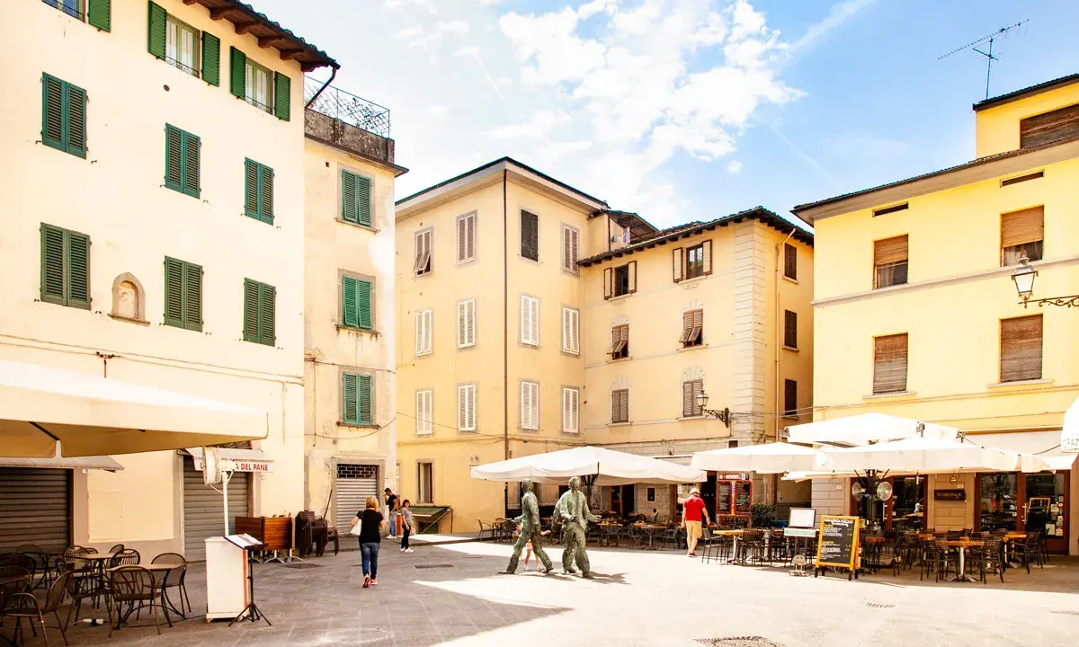 Piazza con edifici storici e tavolini all'aperto, ideale per scoprire cosa vedere a Pistoia in un giorno.
