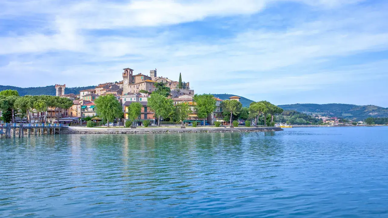 Il borgo più bello del Lago Trasimeno, con le sue case colorate e torri medievali, si specchia nelle acque azzurre.