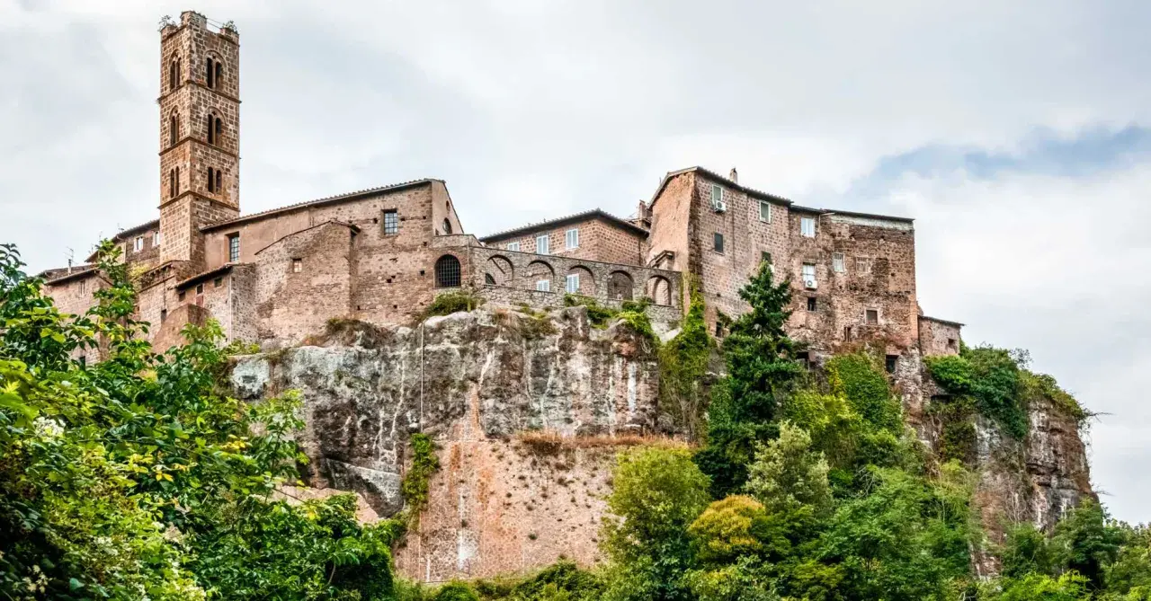 Un borgo medievale arroccato su una rupe, con un'alta torre campanaria. Un esempio dei borghi più belli del Lazio, immerso nel verde.
