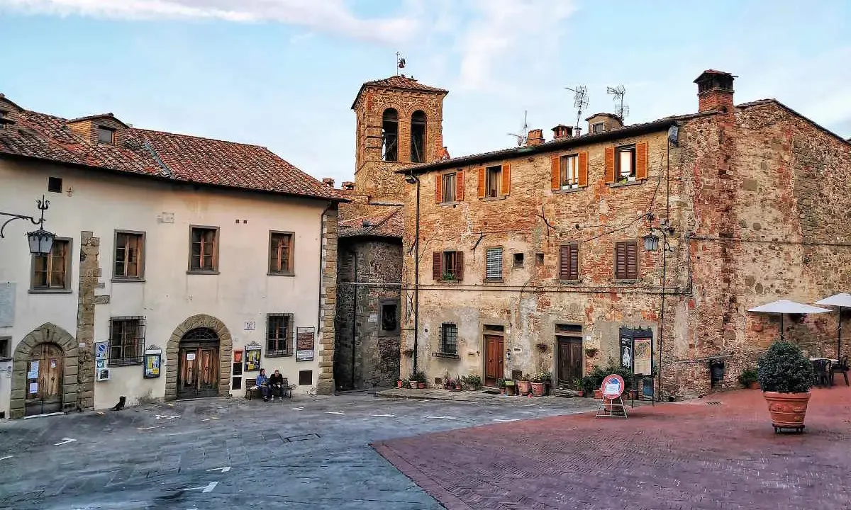 Piazza di un borgo toscano, ideale tra i borghi da visitare in 2 giorni. Edifici in pietra e mattoni, campanile e scorci suggestivi.