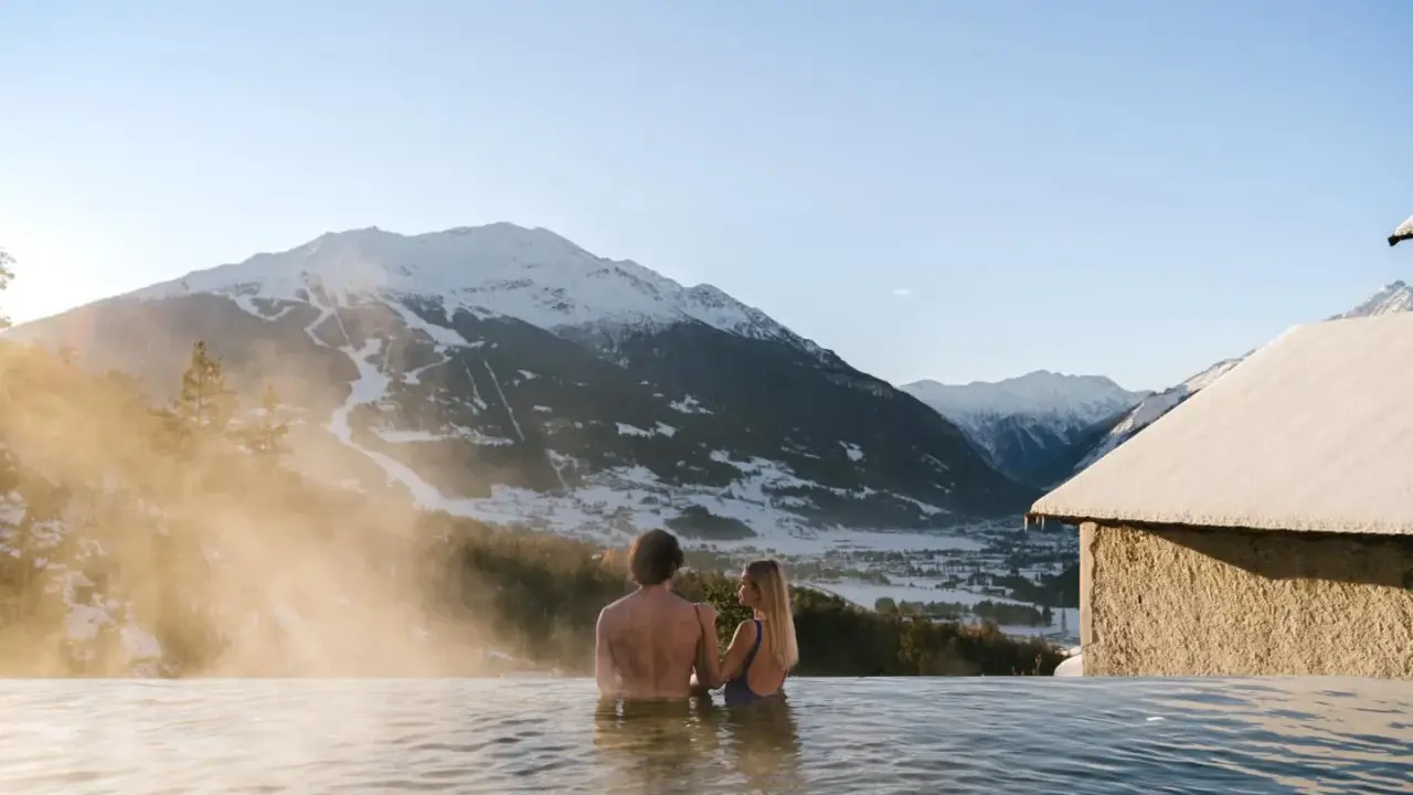 Coppia in una piscina termale con vista sulle montagne innevate. Un'oasi di relax, perfetta per chi cerca terme vicino Milano.