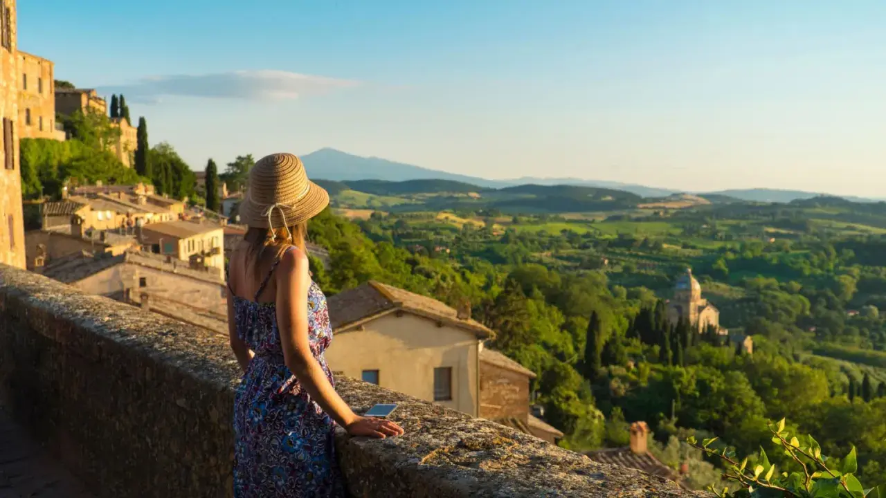 Donna con cappello ammira il panorama collinare toscano, perfetto per scoprire cosa visitare in Toscana in 2 giorni.