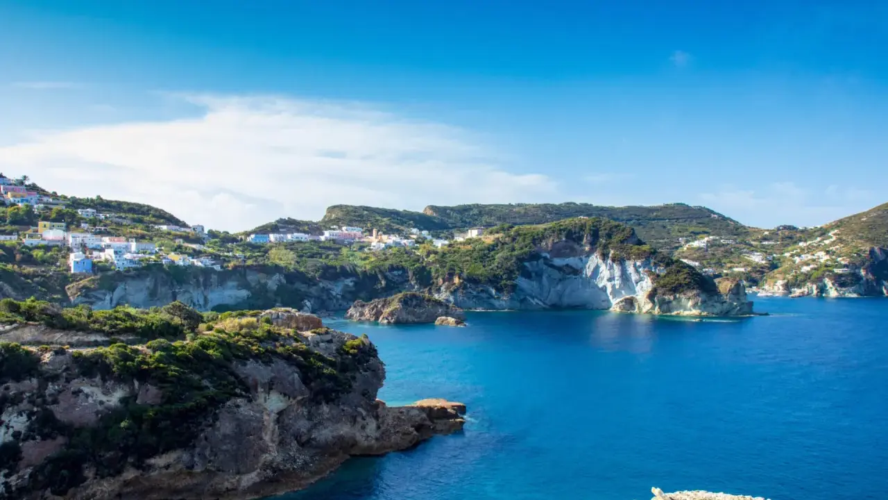 Panoramica della **cala dell'acqua a Ponza**, con case colorate aggrappate alla collina e un mare blu intenso.