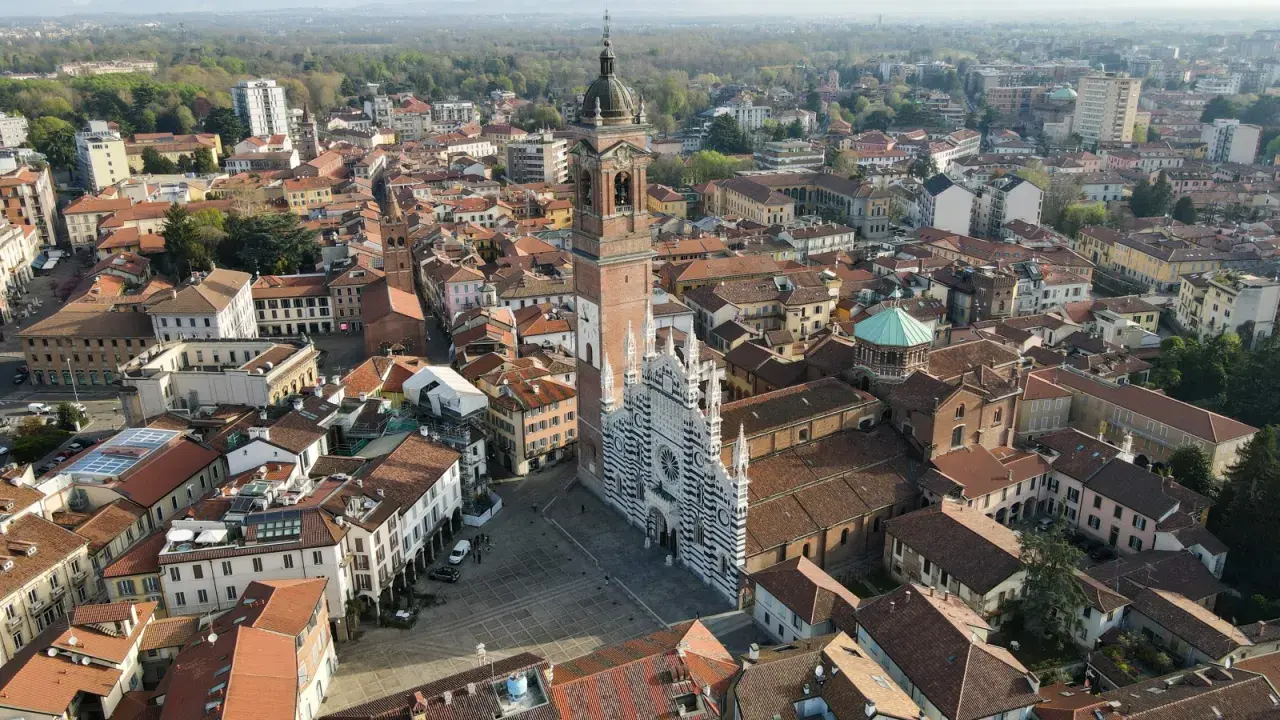 Vista aerea della Duomo di Monza, con la sua facciata a strisce bianche e nere. Si vede il campanile e il centro storico, che mostra dove si trova Monza.