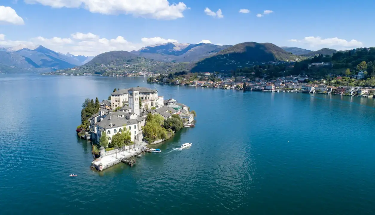 Isola di San Giulio, una gemma nel lago d'Orta, con la città sul mare nord Italia sullo sfondo.