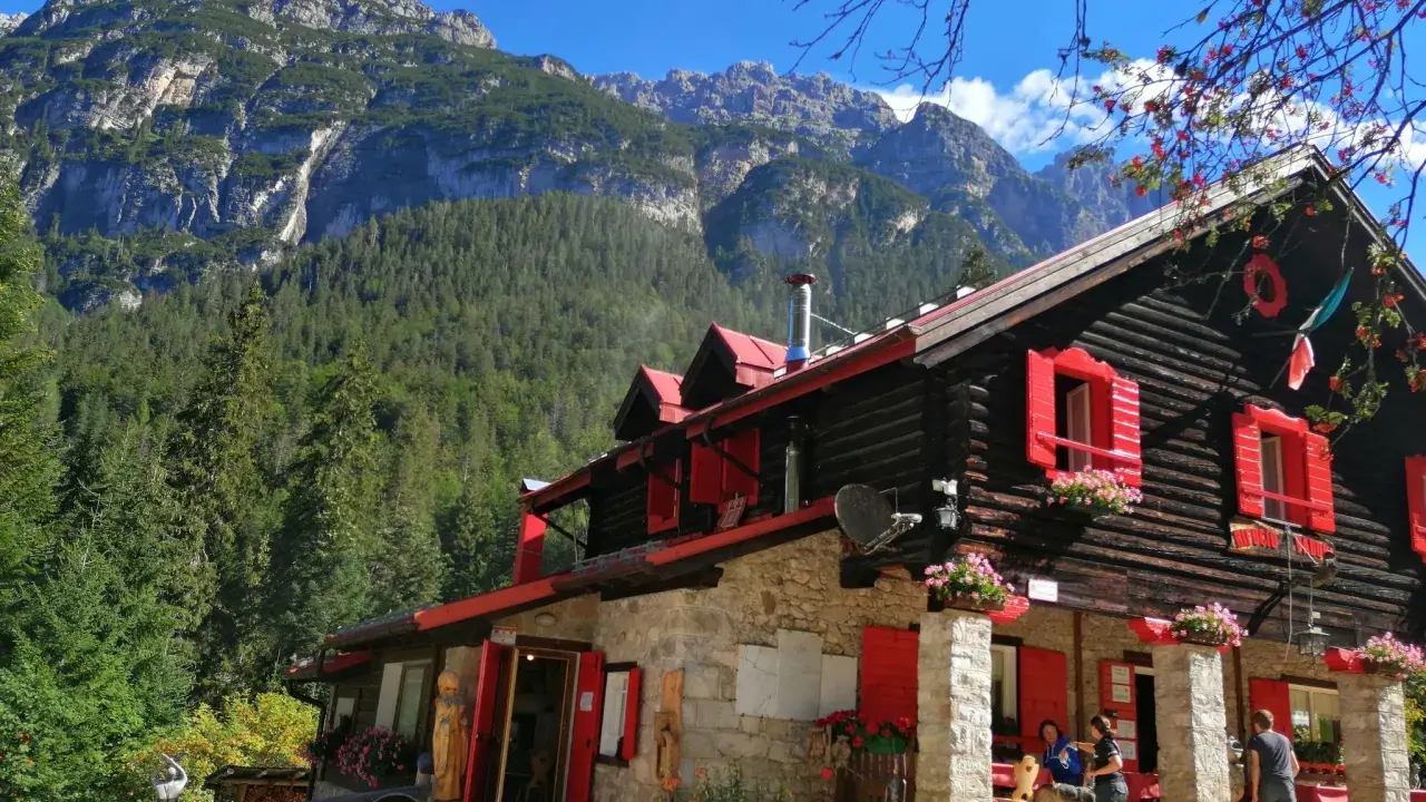 Rifugio con forni di sopra, circondato da boschi e montagne imponenti.