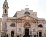 La Cattedrale di San Michele Arcangelo a Sammichele di Bari, con il suo imponente campanile e la facciata in pietra chiara, domina la piazza.