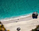 Spiaggia dorata e mare cristallino sulla riviera ligure di ponente. Un pescatore solitario e rocce imponenti.