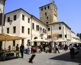 Mercato in piazza a Portobuffolè cosa vedere: bancarelle di antiquariato e la torre civica sullo sfondo.