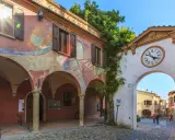 Un angolo suggestivo tra i borghi da visitare in Romagna. Archi affrescati, un portale con orologio e un vicolo acciottolato invitano alla scoperta.