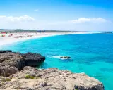 Scogli vulcanici e sabbia bianca su una spiaggia pop corn in Sardegna, con acque turchesi cristalline.