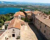 Vista dall'alto del populonia centro storico, con case dai tetti rossi e il mare blu sullo sfondo.
