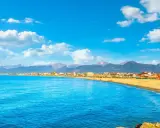 Spiaggia dorata e mare azzurro a Viareggio, con montagne sullo sfondo. Perfetto per scoprire cosa vedere a Viareggio in un giorno.