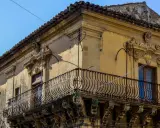 Angolo di un palazzo barocco a Militello in Val di Catania, con balcone in ferro battuto e decorazioni in pietra.
